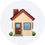 Small beige house with a red roof, chimney, blue window, brown door, and green bushes on a light gray circular background.
