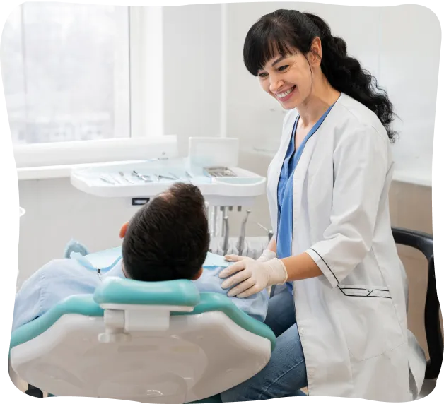 Smiling female dentist in white coat consulting a male patient reclining in a dental chair.